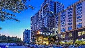 A multi-story hotel with a modern design, featuring a prominent entrance and a parking lot in front. - JINGDUHUI Hotel (Dongguan)