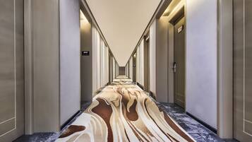 Un couloir d’hôtel avec un tapis à motifs, des portes des deux côtés et un panneau indiquant le numéro de chambre 2012.
