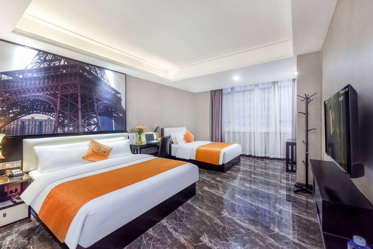 A hotel room with two beds, a large screen displaying the Eiffel Tower, a flat-screen TV, and a marble floor.