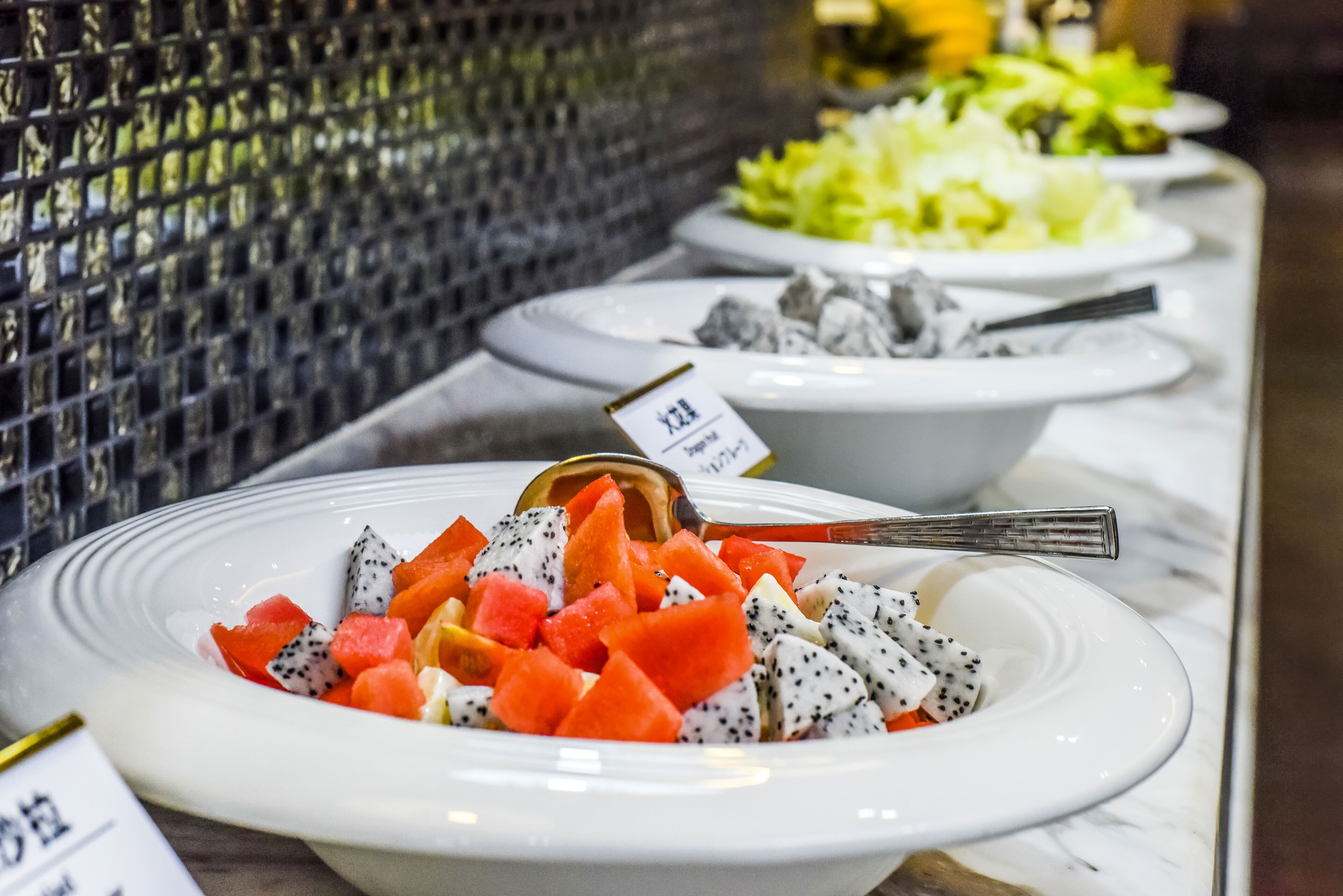 A buffet with various dishes, including fruit and a salad.