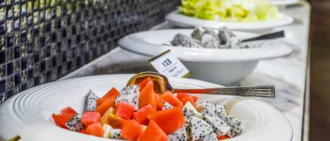 A buffet with various dishes, including fruit and a salad.