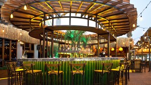 An outdoor bar area with a wooden pergola, seating, and a bar counter. - Kerman Hotel (Cesme)