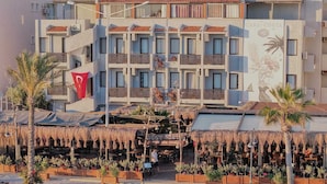 A coastal building with a terrace, outdoor seating, and a view of the sea. - Kerman Hotel (Cesme)