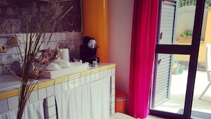 A kitchen with a dining area, a coffee machine, and a window with curtains. - Casa Aurora (Taormina)