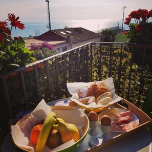 A balcony with a table set with bread, eggs, and fruit. - Casa Aurora (Taormina)