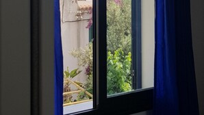 A window with a view of a building and some greenery. - Casa Aurora (Taormina)
