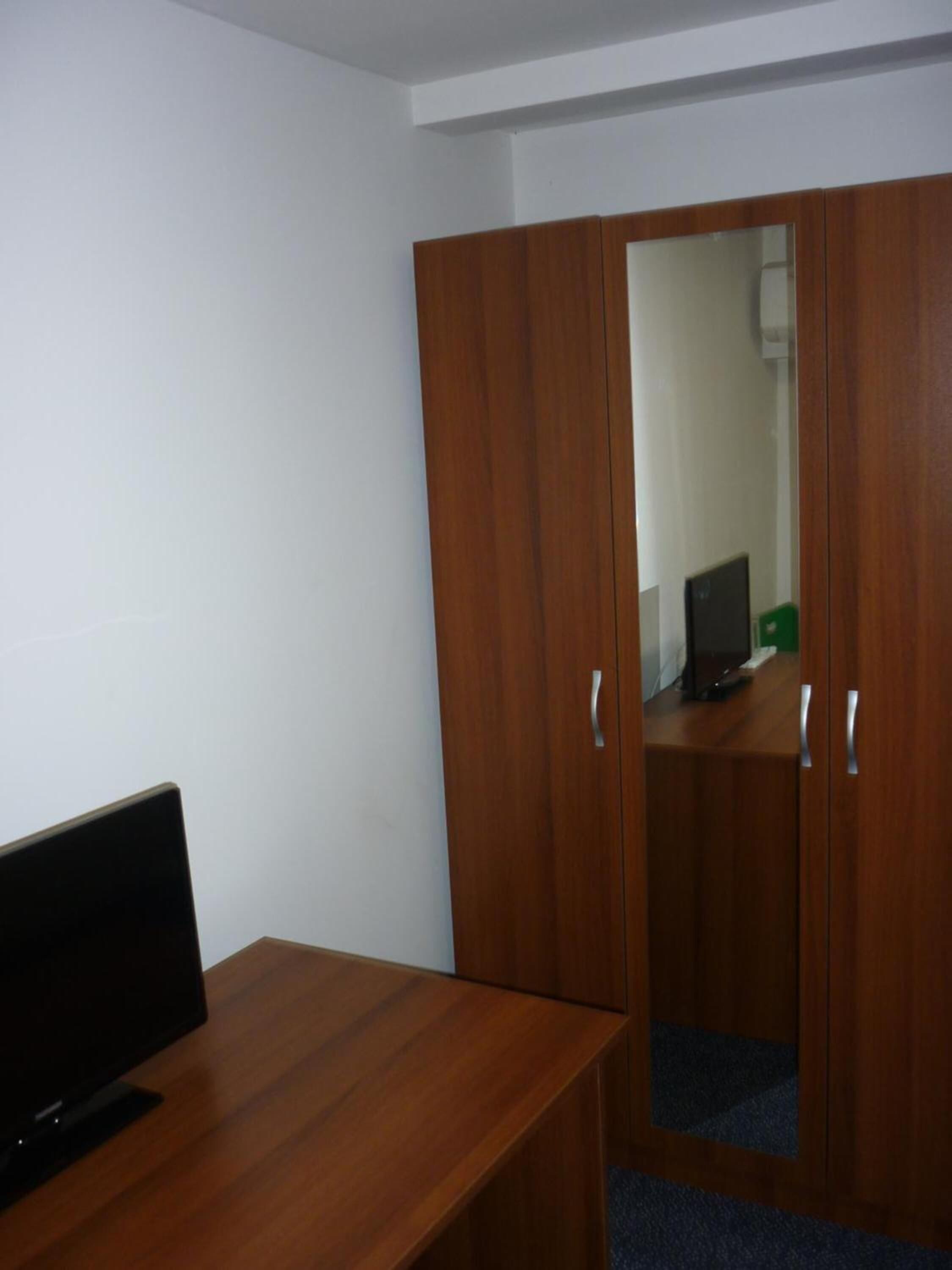 Een kamer met een houten bureau, een kast en een spiegel.