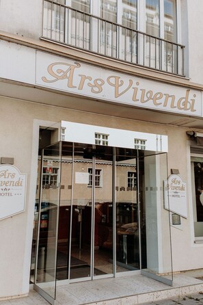 La entrada de un hotel con puerta de vidrio y un letrero que dice "Ars Vivendi HOTEL".