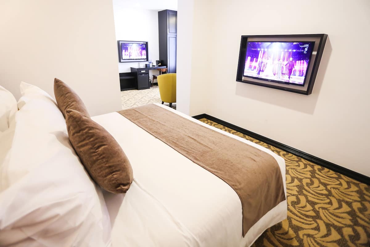 Une chambre d’hôtel avec un lit, un téléviseur fixé au mur et un bureau avec une chaise.
