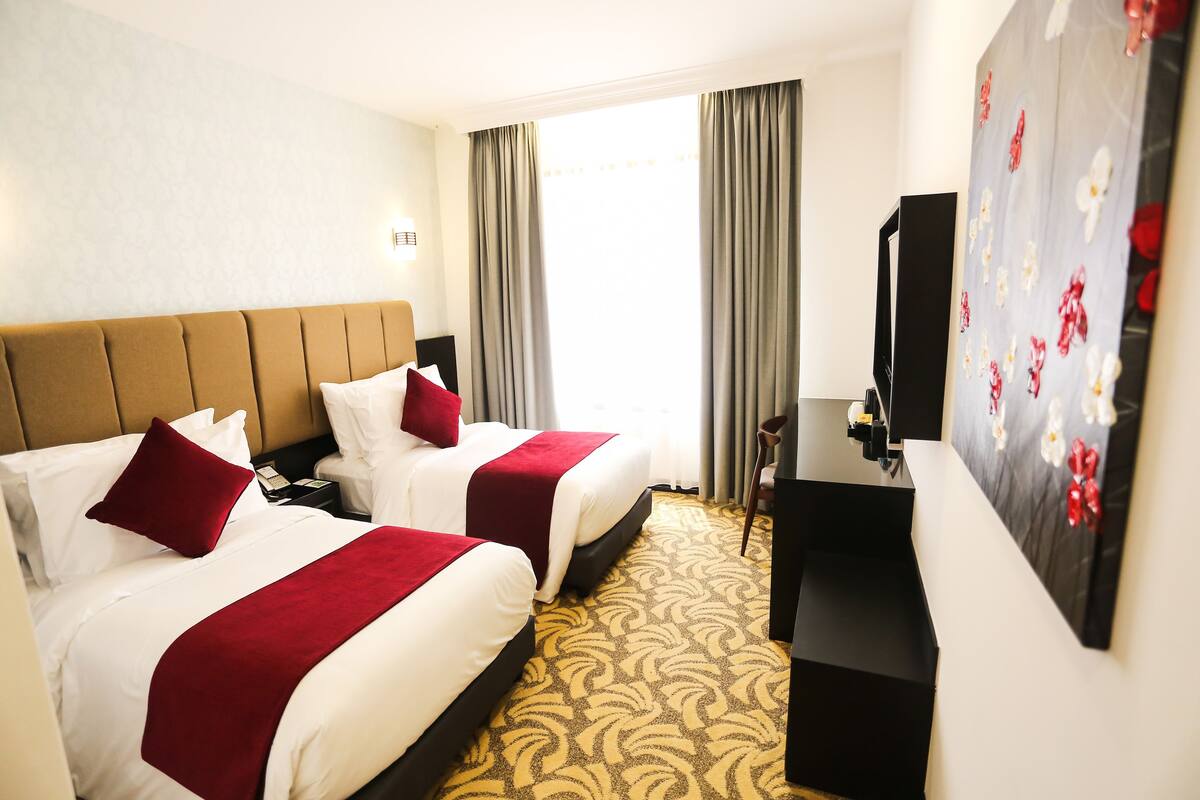 Une chambre d’hôtel avec deux lits, une télévision et un tableau au mur.