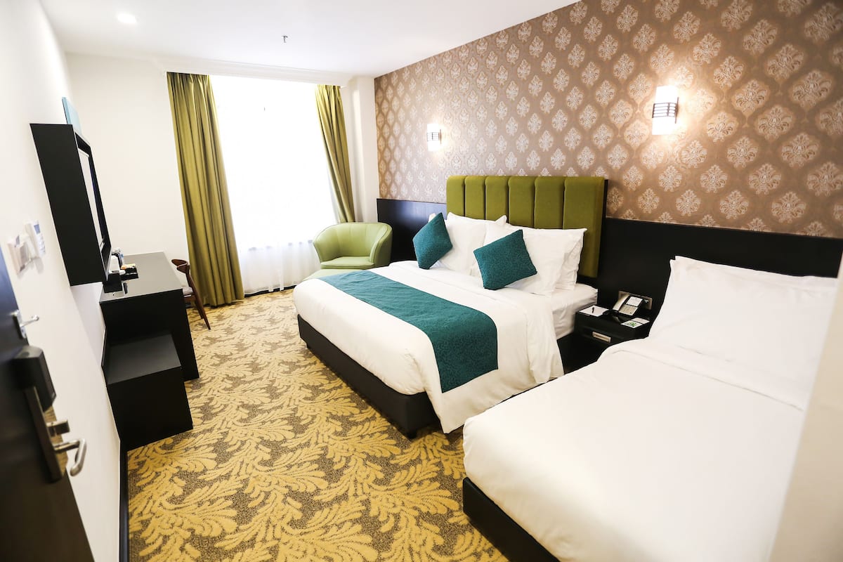 Une chambre d’hôtel avec deux lits, un bureau, une chaise et une moquette à motifs.