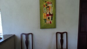 Dos sillas de madera con asientos de mimbre frente a una pared con un cuadro abstracto de colores.