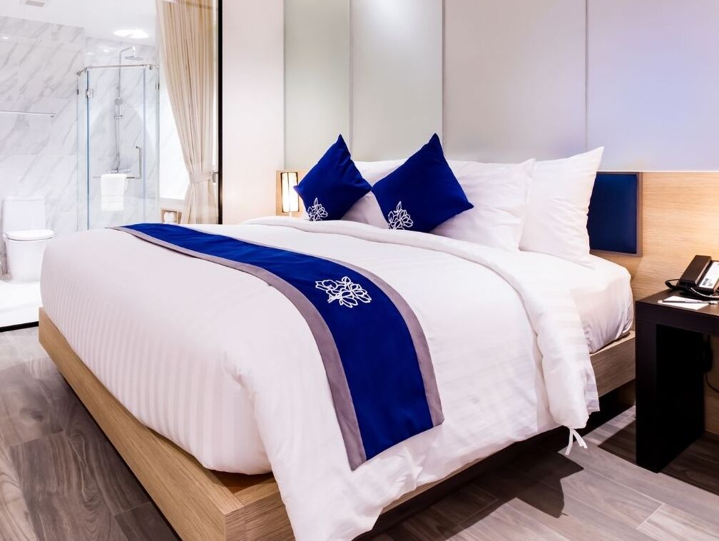 Una habitación de hotel moderna con una cama grande, una mesita de noche con teléfono y una zona de ducha.