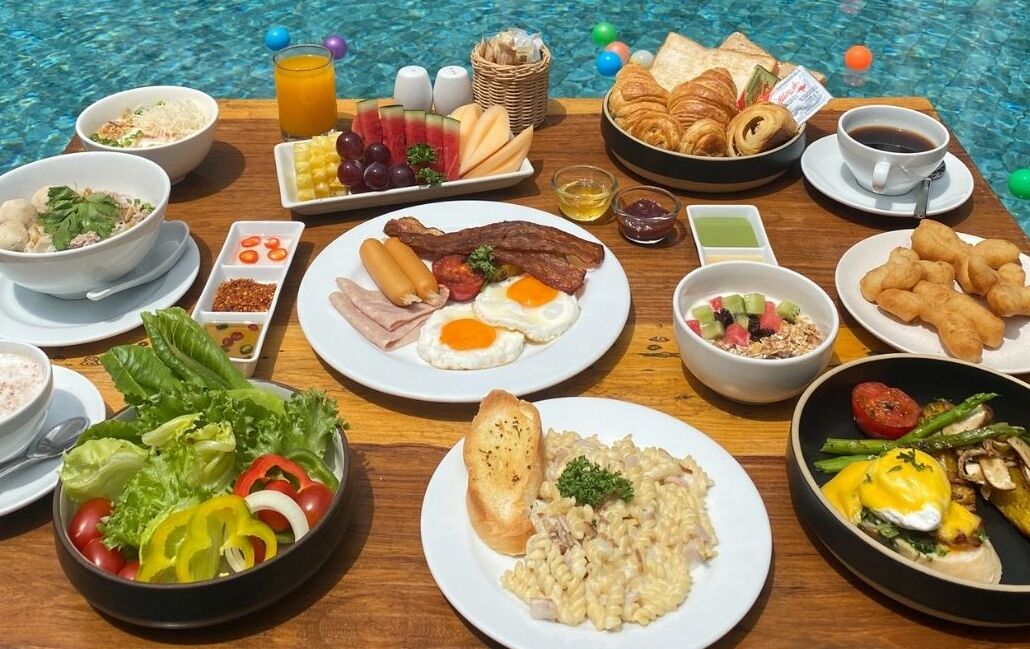 Buffet de l'esmorzar amb diferents plats i una piscina al fons.