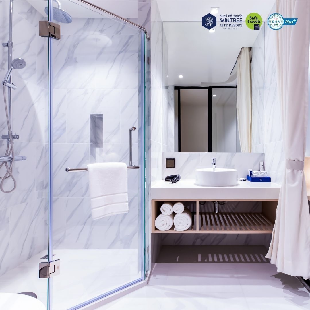 A modern bathroom with a glass-enclosed shower, a white sink, and a mirror above it.