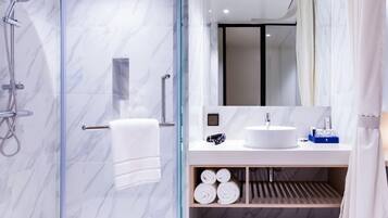 A modern bathroom with a glass-enclosed shower, a white sink, and a mirror above it.