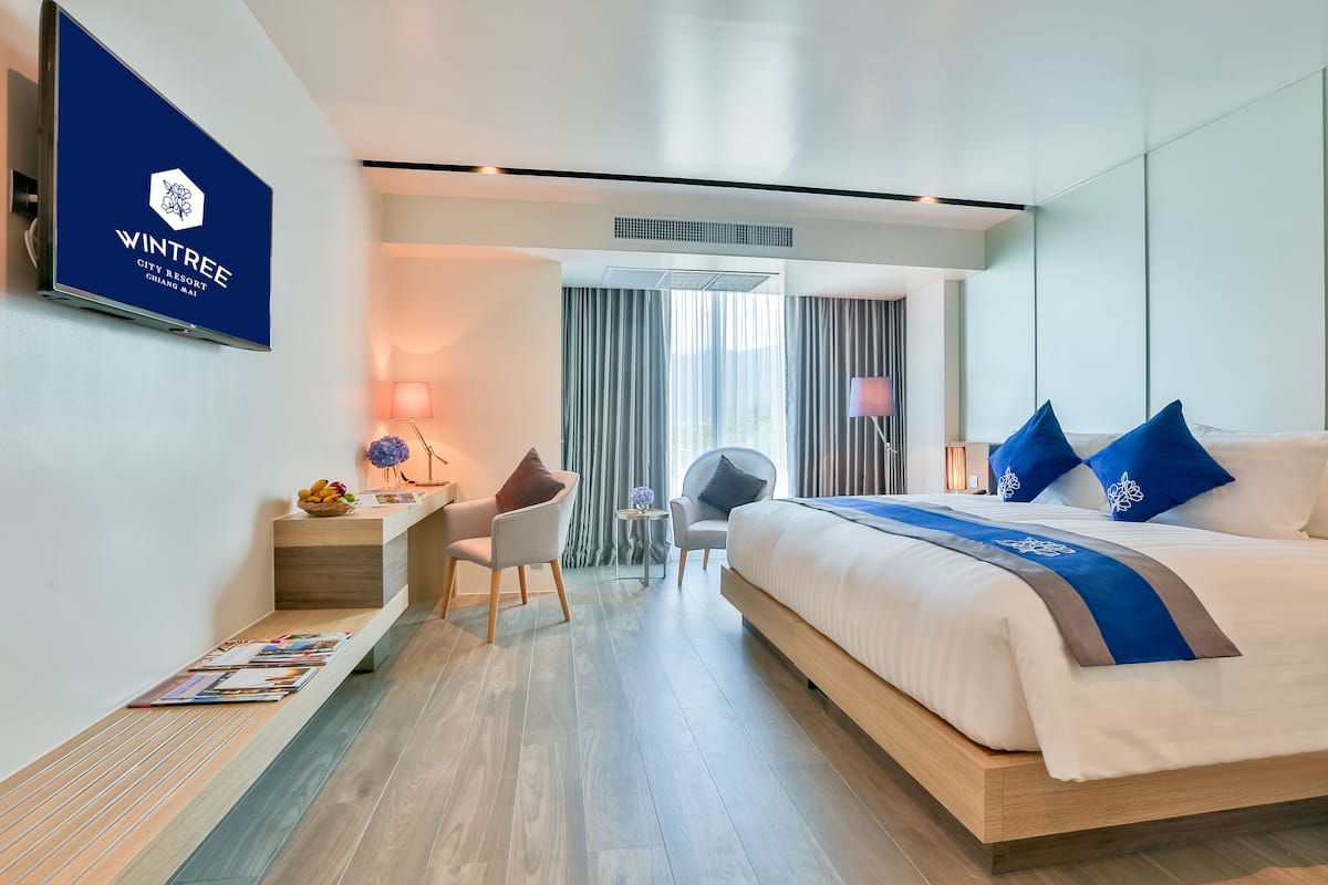 A modern hotel room with a bed, desk, and seating area.