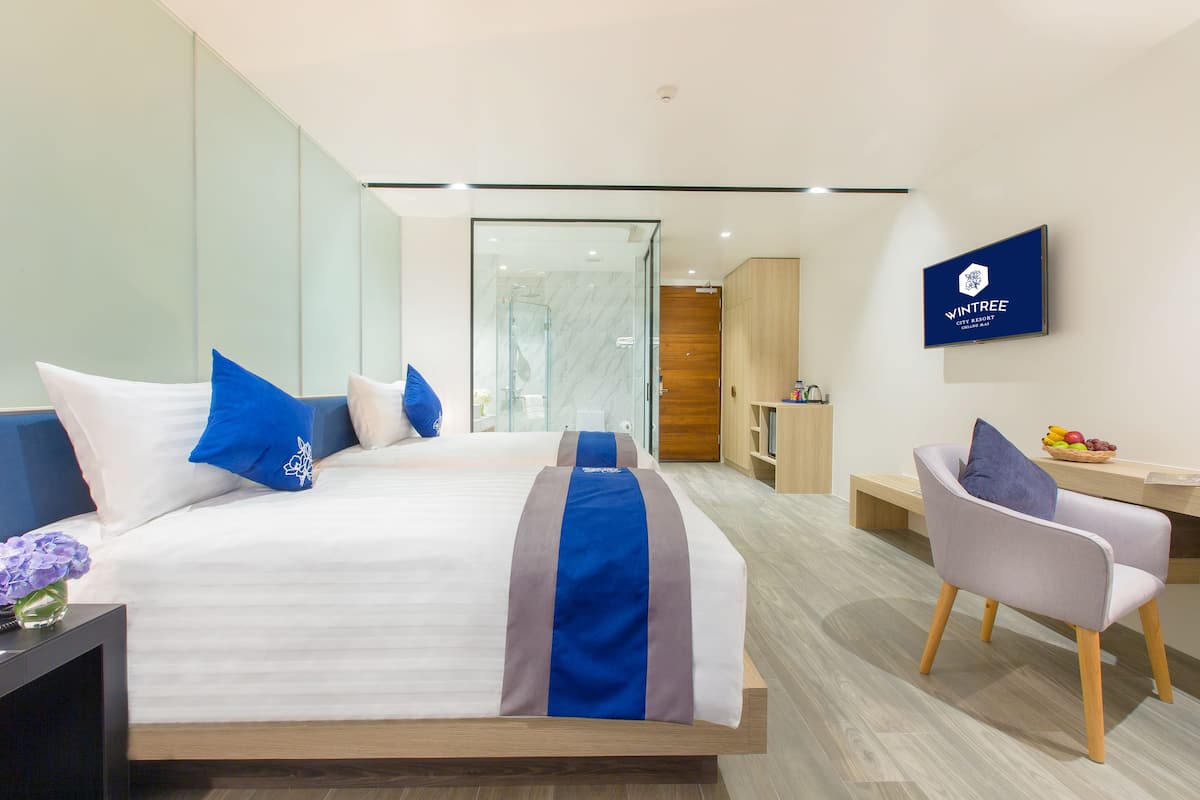 A modern hotel room with a large bed, a desk, and a television.