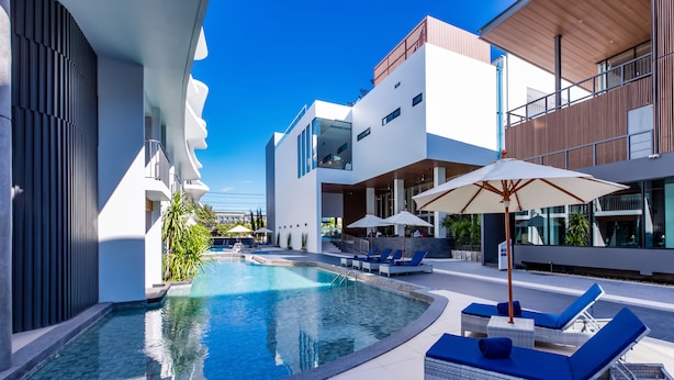 A modern pool area with lounge chairs and umbrellas, surrounded by contemporary buildings. - Wintree City Resort Chiang Mai (Chiang Mai)
