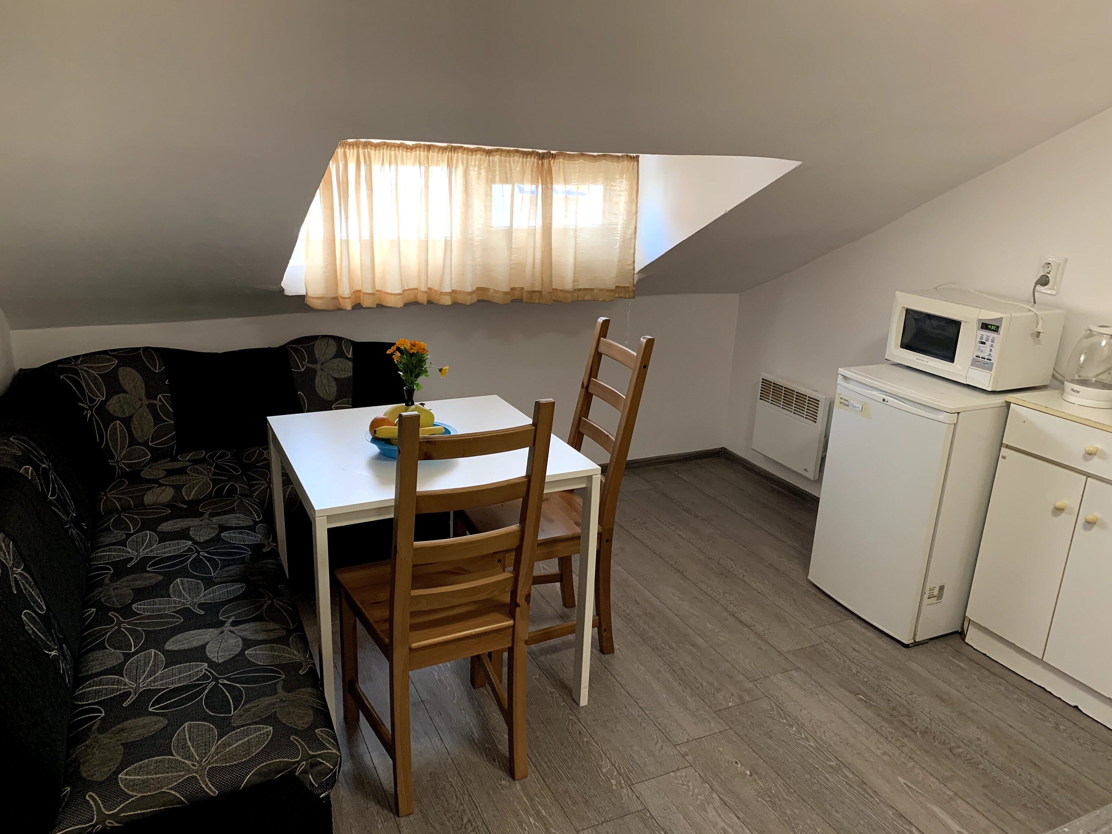 A compact kitchenette with a microwave, a small refrigerator, and a dining area with a table and chairs.