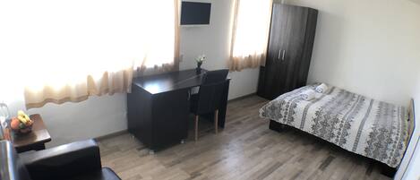 A compact room with a bed, a desk, and a chair.