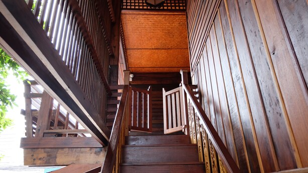 A wooden staircase with a handrail and a wooden railing on one side.