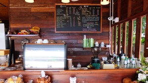 A café with a wooden interior, a chalkboard menu, and various coffee and milk options.