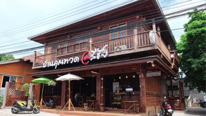 A wooden building with a balcony, outdoor seating, and a sign.