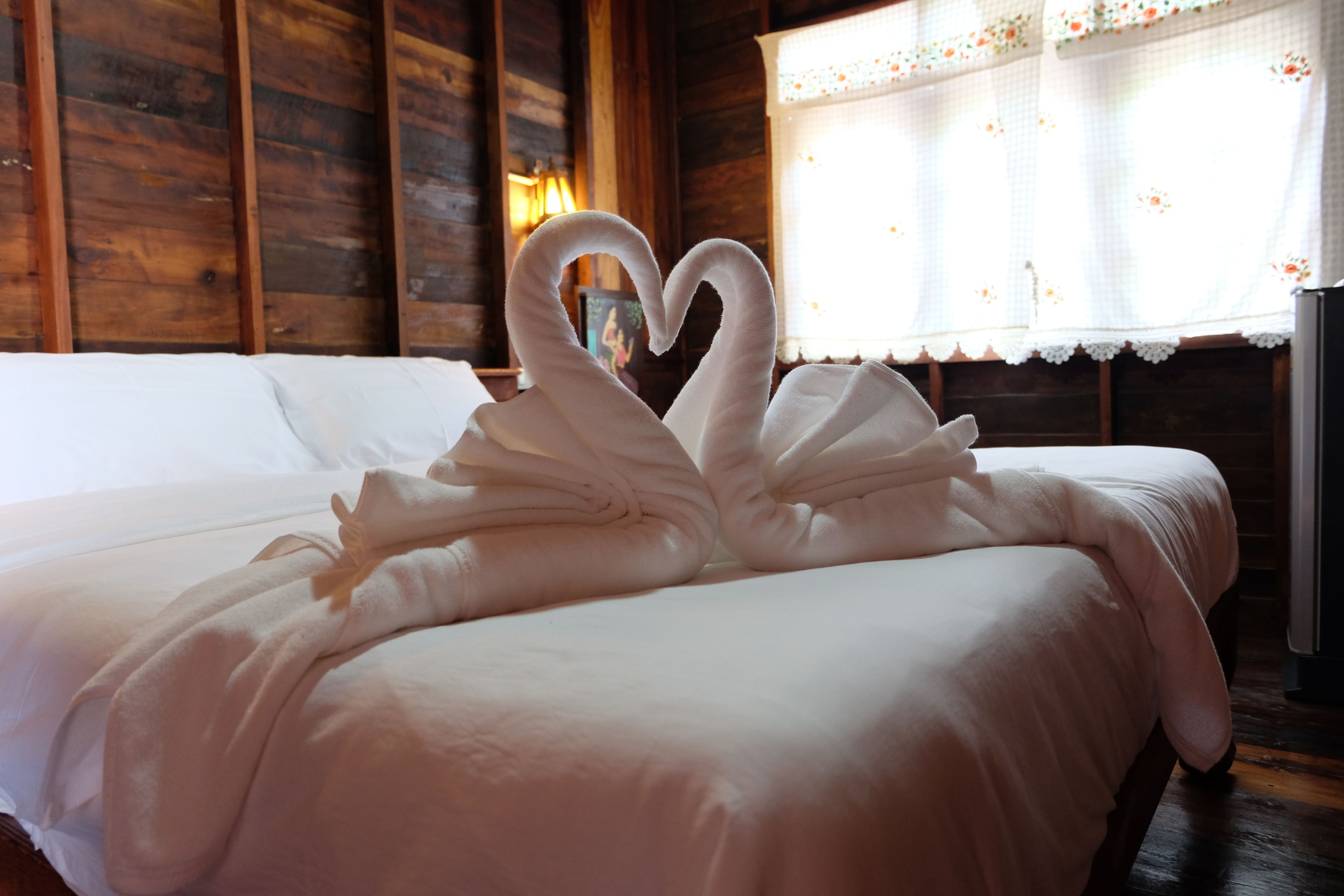 Un lit décoré avec des serviettes disposées en forme de cœur.