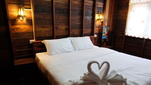 A wooden-paneled room with a bed, two wall-mounted lights, and a picture frame on the wall.