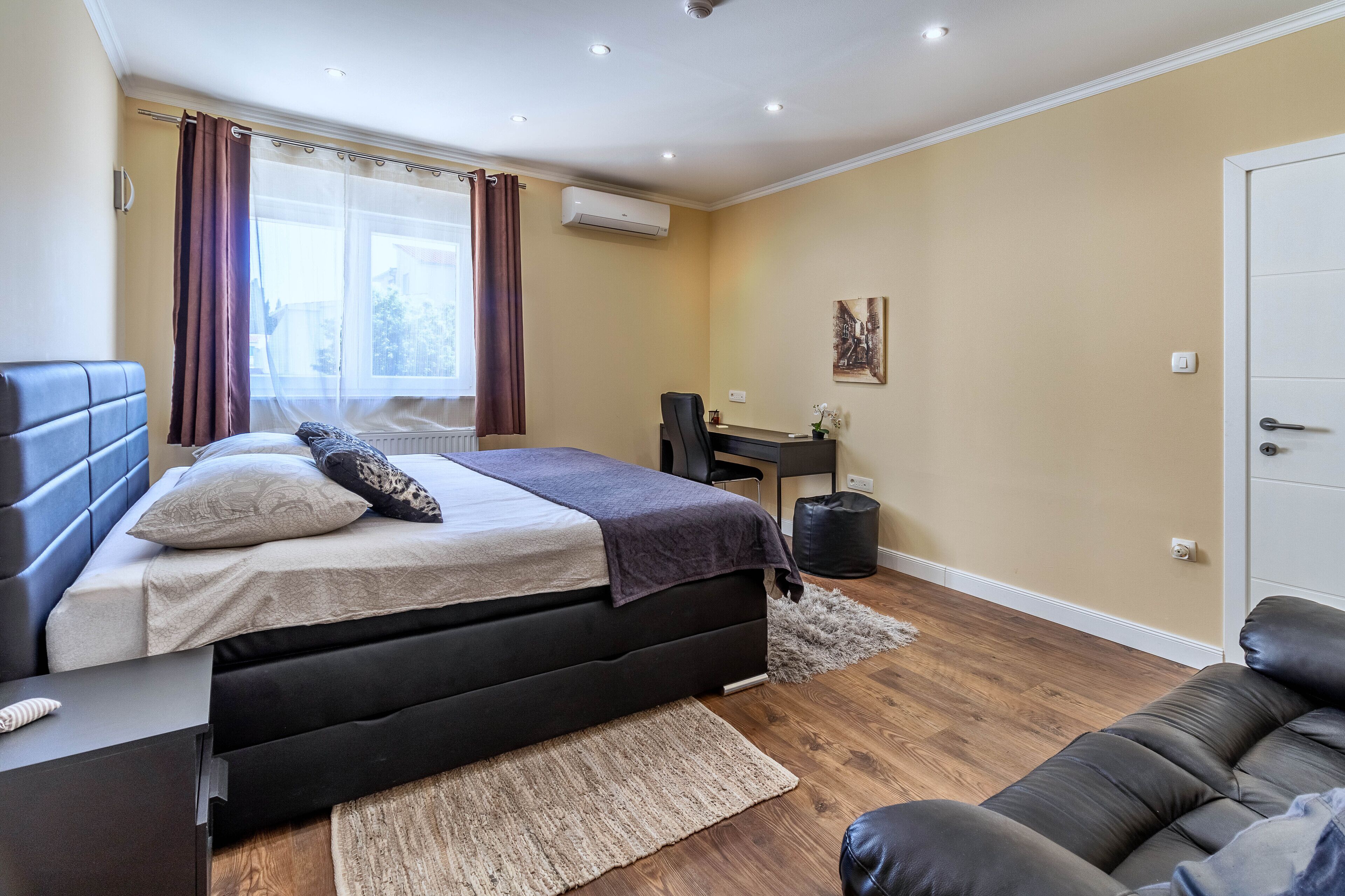 A bedroom with a bed, a desk, a chair, and a couch.