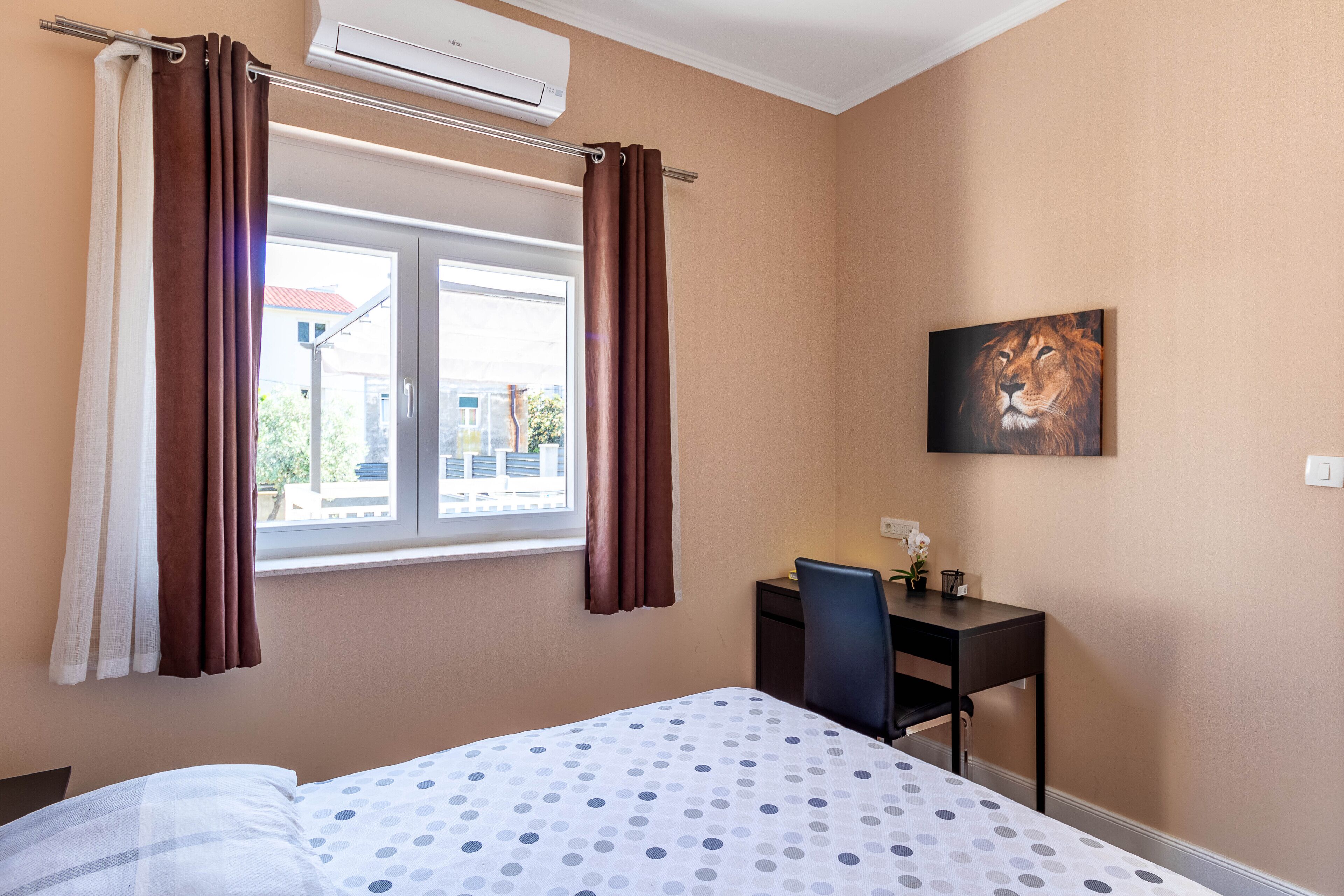 Una habitación de hotel con cama, escritorio y ventana con cortinas.