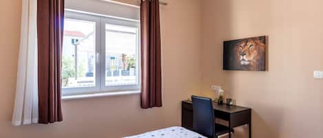 Una habitación de hotel con cama, escritorio y ventana con cortinas.