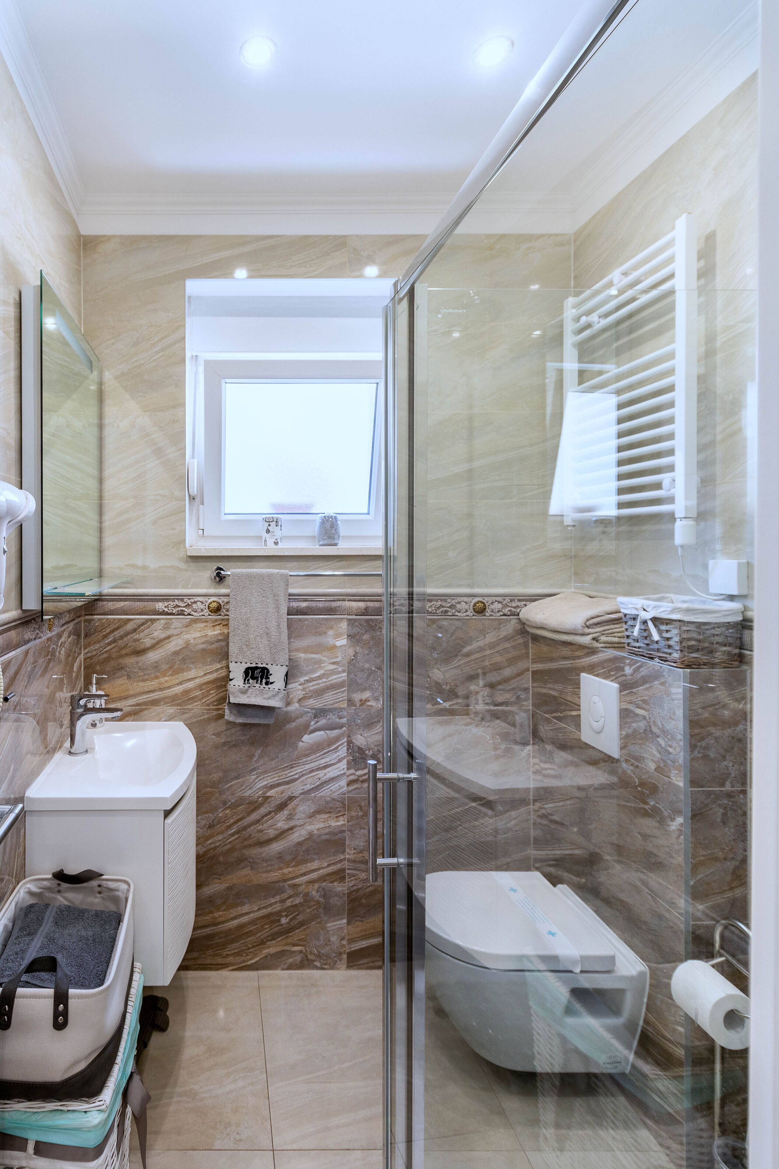 A modern bathroom with a glass-enclosed shower, a sink, a toilet, and a vanity with a mirror.