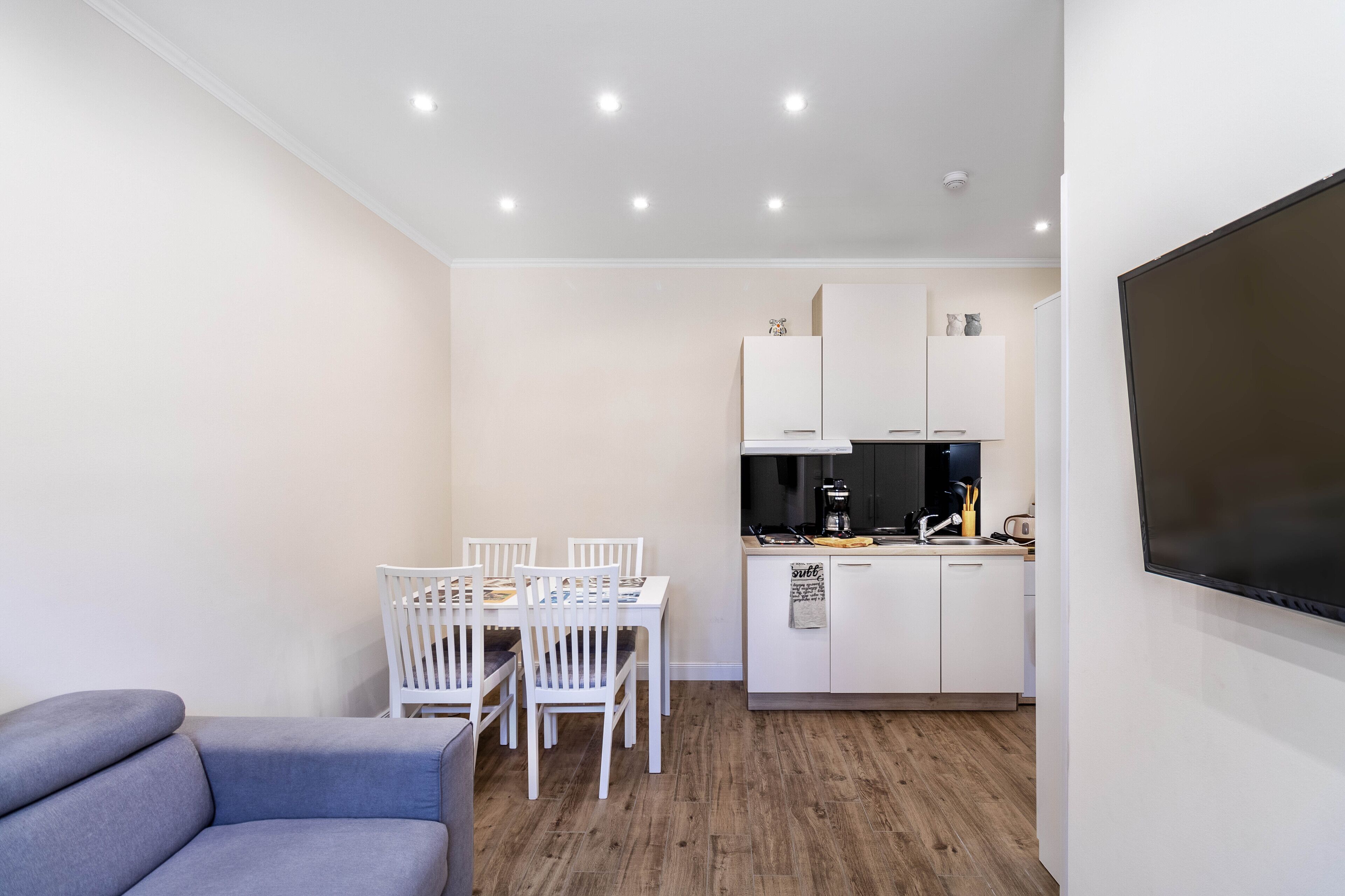 A compact living space with a dining area, kitchenette, and a gray sofa.
