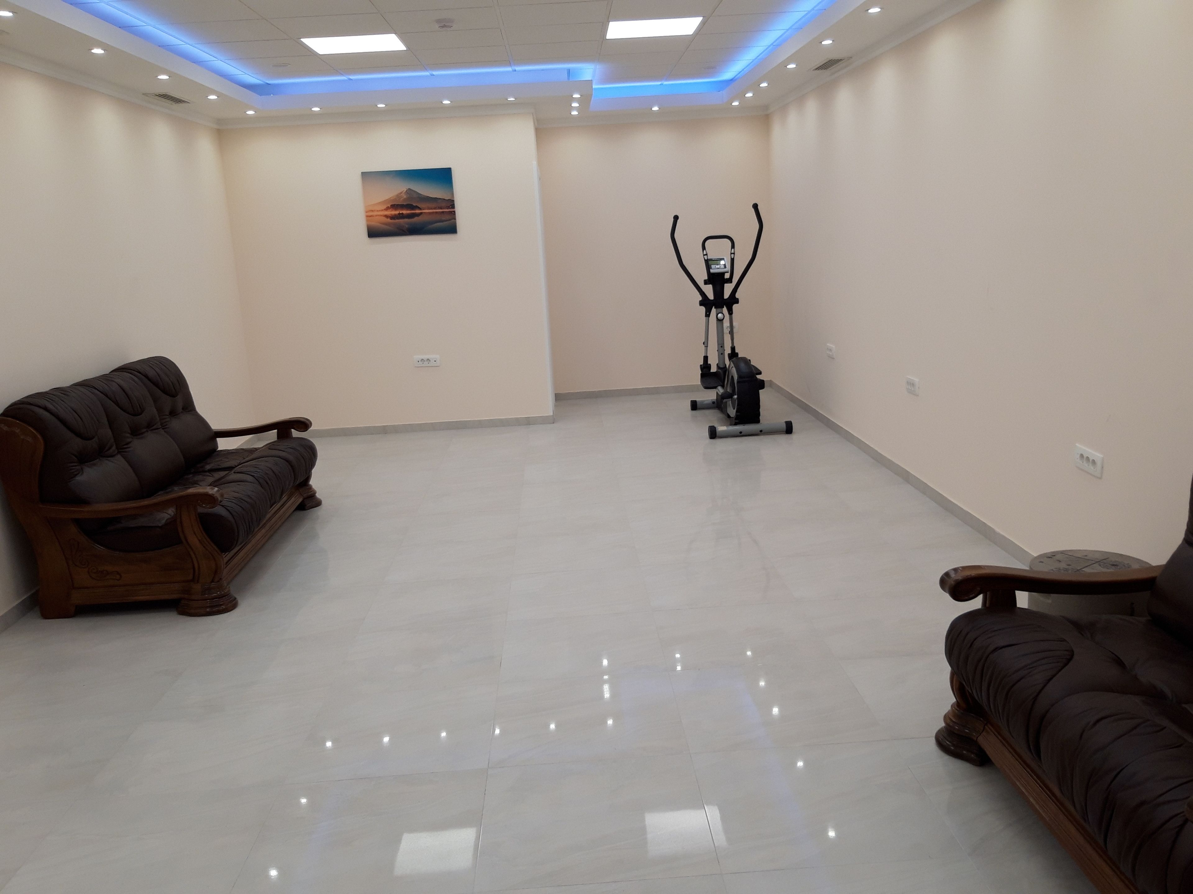 A spacious room with a large exercise bike, two wooden sofas, and a painting on the wall.