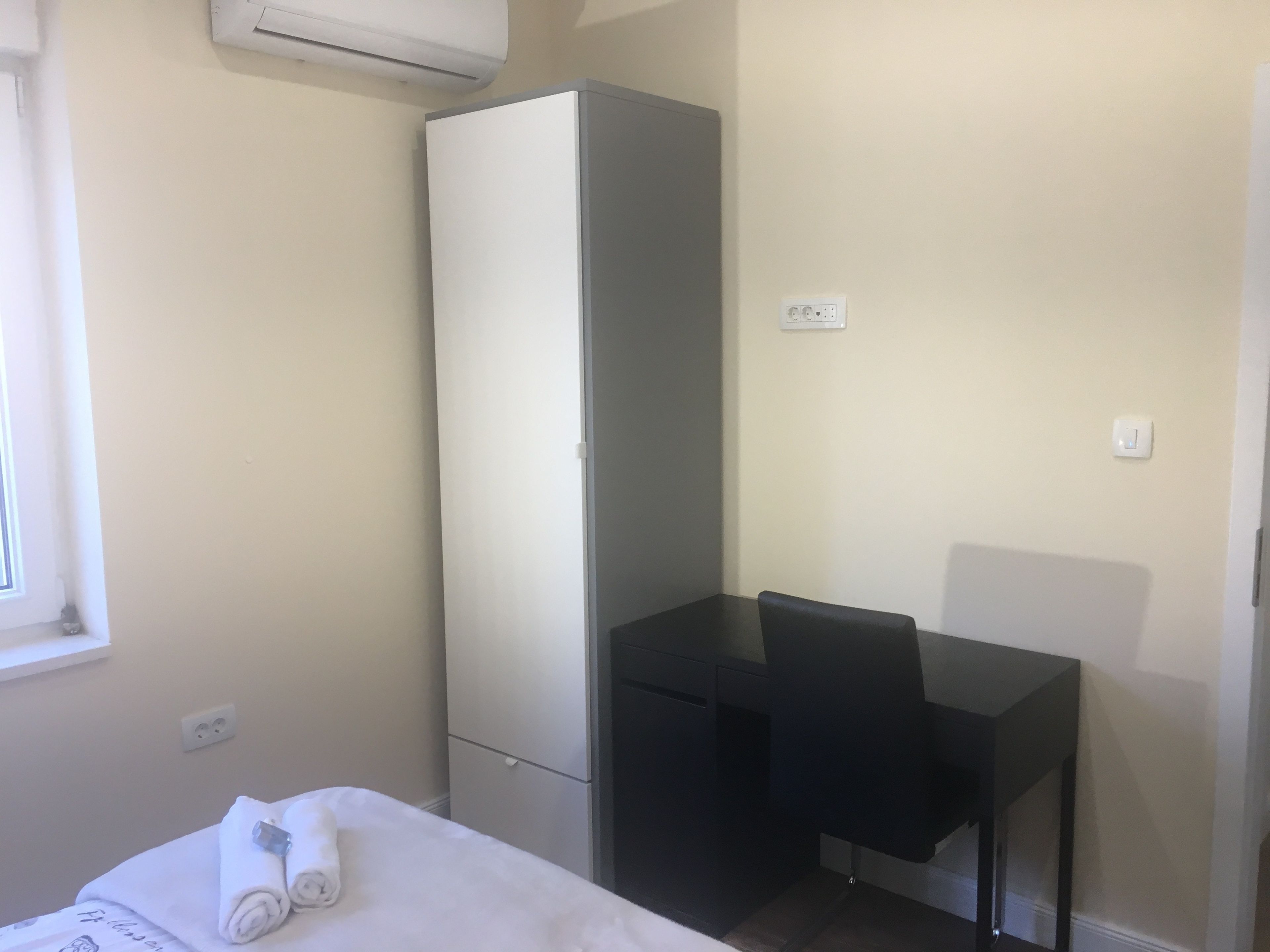 A small, clean room with a bed, a desk, and a wardrobe.