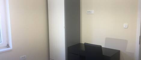 A small, clean room with a bed, a desk, and a wardrobe.