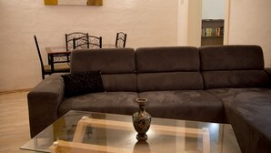 Ein modernes Wohnzimmer mit Glastisch, dunkelbrauner Couch und einem Gemälde an der Wand.