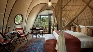 A bedroom with a canopy bed, a round table, two chairs, and a view of the outdoors. - Wild Coast Tented Lodge - Relais and Chateaux - All Inclusive (Tissamaharama)