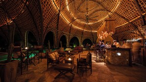 An indoor setting with a high, arched ceiling structure, stone flooring, and seating arrangements.