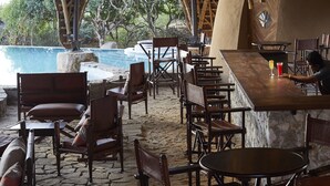 An outdoor seating area with wooden furniture and a thatched roof structure.
