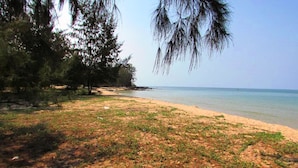 A beach with sand, sparse vegetation, and trees. - Orchard Fruit Farm Bungalow (Phu Quoc)