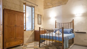 Un dormitorio con piso a cuadros, un armario de madera, estructura de cama metálica y una ventana con vistas.