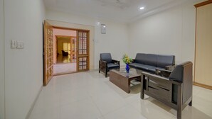 A modern living room with a sofa, two armchairs, a coffee table, and a decorative vase. - Khyathi Hotels (Hyderabad)