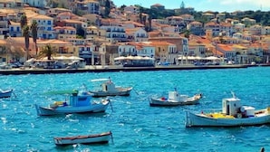 Uma cidade costeira com edifícios ao longo da orla, barcos atracados na água e um céu azul claro.