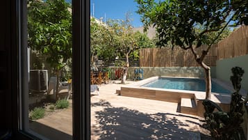 A backyard with a swimming pool, wooden deck, and a view through a glass door.