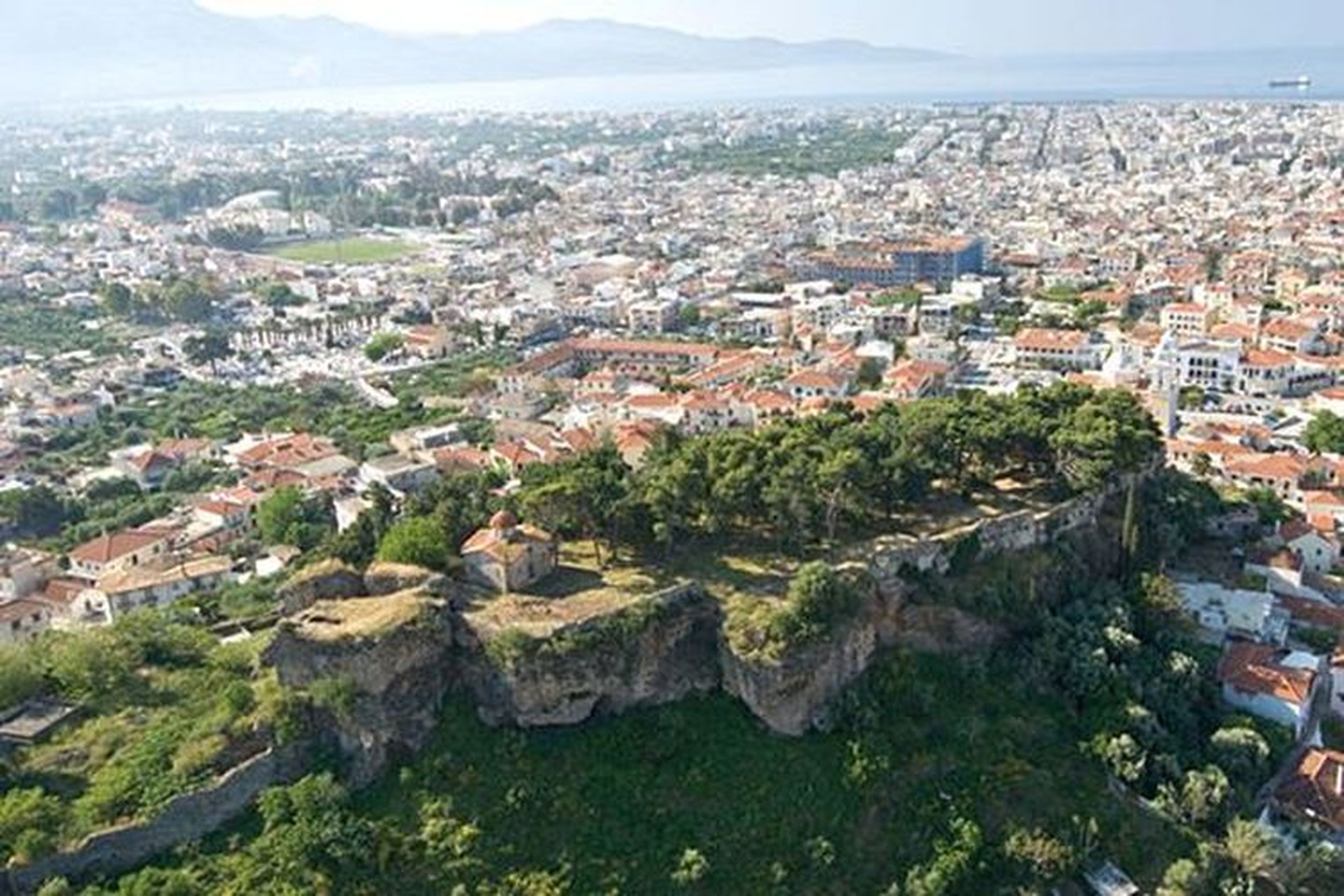 Un paysage urbain côtier avec une formation rocheuse imposante au premier plan.