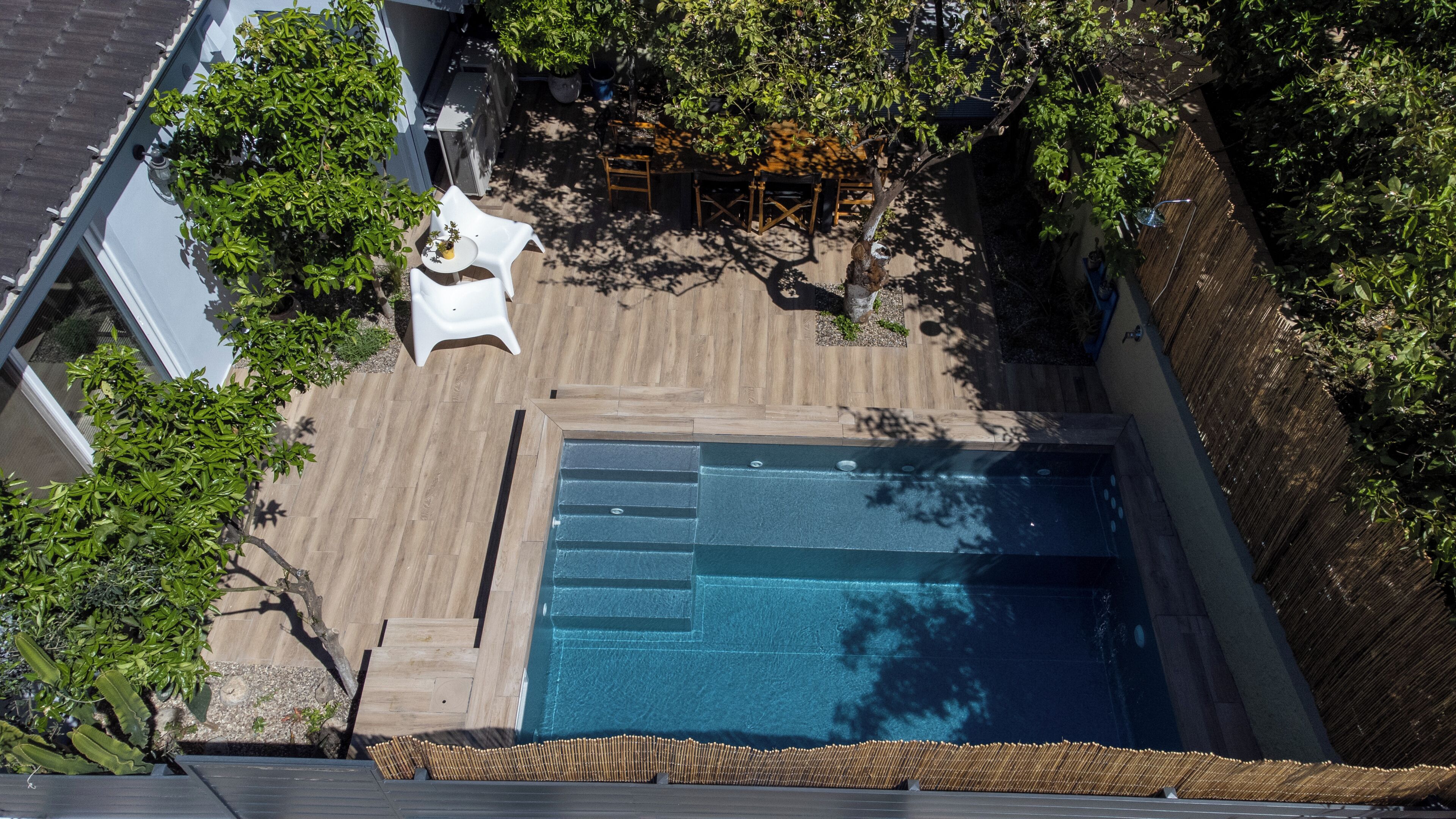 Ein Pool auf dem Dach mit einer Holzterrasse, umgeben von Bäumen und einem weißen Stuhl.