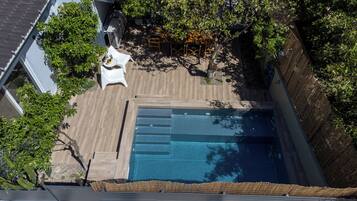 Ein Pool auf dem Dach mit einer Holzterrasse, umgeben von Bäumen und einem weißen Stuhl.